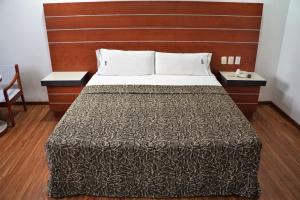 um quarto com uma cama grande e uma cabeceira em madeira em Hotel Duque em Cidade do México