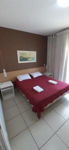 1 dormitorio con 1 cama roja y 2 toallas en Village Aldeia das Águas, en Ipiabas