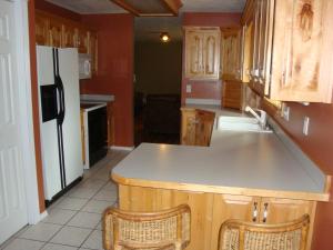 uma cozinha com armários de madeira e um frigorífico branco em Geyser Mountain Home em West Yellowstone