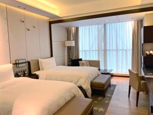 una camera d'albergo con due letti e un soggiorno di HUALUXE Hotels & Resorts Nanchang High-Tech Zone, an IHG Hotel a Nanchang