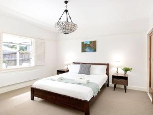 a white bedroom with a bed and a chandelier at Kookaburra Cottage in Bowral