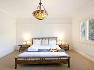 a bedroom with a bed and a chandelier at Kookaburra Cottage in Bowral