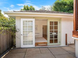 a small home with a door open to a patio at Kookaburra Cottage in Bowral +16 photos