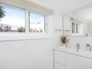 a white bathroom with a sink and a window at Kookaburra Cottage in Bowral