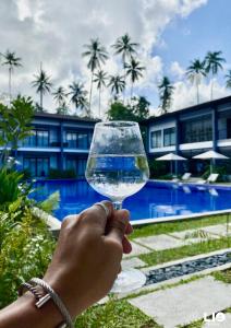 a person holding a wine glass in front of a swimming pool at Huni Lio in El Nido