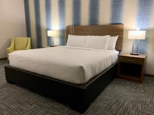 a bed in a hotel room with two lamps and a chair at Meridian Inn & Suites Regina Airport in Regina