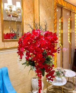 a vase filled with red flowers on a table at Vân Trang Hotel in Vĩnh Long