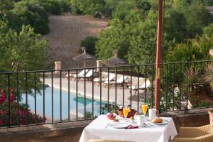 a table with food and drinks on a balcony with a pool at Fincahotel Can Estades in Calvià