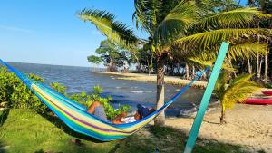 a man laying in a hammock on a beach at Seaside Chateau Resort in Belize City +135 photos