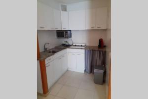 a small kitchen with white cabinets and a sink at Apartamento con piscina en el centro de Blanes in Blanes