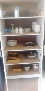 a white pantry with plates and dishes on shelves at Shanduka Country Lodge in Thohoyandou
