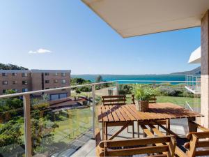 a balcony with a wooden table and chairs and a view at Promenade, 12 8 Intrepid Cl - fantastic waterfront unit with air con and WiFi in Nelson Bay