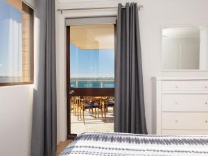 a bedroom with a view of the ocean from a balcony at Promenade, 12 8 Intrepid Cl - fantastic waterfront unit with air con and WiFi in Nelson Bay