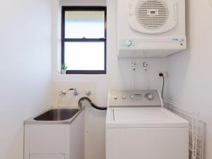 a small white kitchen with a sink and a window at Promenade 12, 8 Intrepid Cl - fantastic waterfront unit with air con and Wifi in Nelson Bay