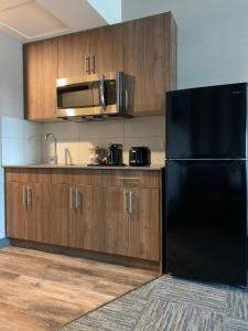a kitchen with a black refrigerator and wooden cabinets at Meridian Inn & Suites Regina Airport in Regina
