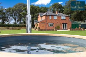 uma piscina de água em frente a uma casa em Luxury Four Bed Country House With Hot Tub - Woodchurch near to Ashford em Ashford