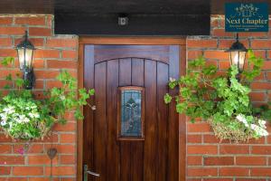 uma porta de madeira numa parede de tijolos com plantas em Luxury Four Bed Country House With Hot Tub - Woodchurch near to Ashford em Ashford