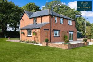 a large brick house with a green lawn at Luxury Four Bed Country House With Hot Tub - Woodchurch near to Ashford in Ashford