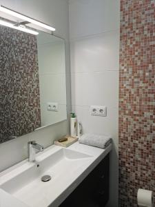 een badkamer met een witte wastafel en een spiegel bij Dos habitaciones dobles en apartamento confortable in Hospitalet de Llobregat