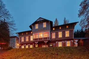 a large wooden house on top of a hill at Penzion Flora in Janske Lazne