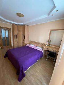 a bedroom with a large purple bed and a desk at Apartment Mala Zhytomyrska 10 in Kyiv