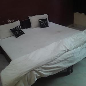 uma grande cama branca com quatro almofadas em shri bake bihari guest house em Gwalior