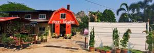mały czerwony dom z roślinami przed nim w obiekcie ชายเขาโฮมสเตย์ w mieście Kanchanaburi