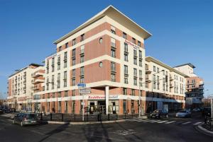 een groot bakstenen gebouw op een straat met auto's geparkeerd voor bij Residhome Paris-Evry in Courcouronnes