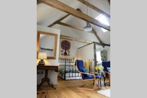 a room with a bed and a desk and chairs at Rural 17th century barn studio apartment in Cheriton Bishop
