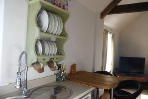 een keuken met een wastafel en een tafel met borden bij Rural 17th century barn studio apartment in Cheriton Bishop