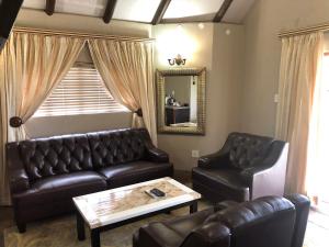 a living room with leather couches and a mirror at Gaggle Inn Guest Lodge in Kroonstad