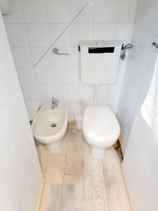 a white bathroom with a toilet and a sink at Porta Venezia & Giardini Montanelli Cozy Flat in Milan