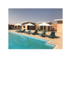 a swimming pool with chairs and umbrellas at Arabian Nights Resort & Spa in Shāhiq