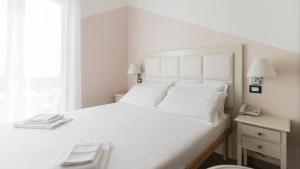 a white bedroom with a large white bed and a window at Residence Il Poggio in Marina di Andora