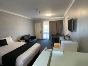 a hotel room with a bed and a living room at Old Maitland Inn in Maitland