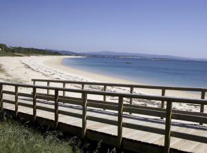 eine hölzerne Promenade an einem Strand neben dem Wasser in der Unterkunft Piso cerca de la playa in Boiro