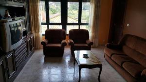 a living room with a couch and two chairs and a table at Piso cerca de la playa in Cerceda
