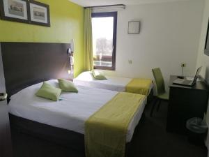 um quarto de hotel com duas camas e uma secretária e uma janela em Enzo Hotels Vierzon by Kyriad Direct em Vierzon