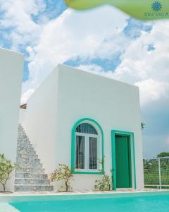 um edifício branco com uma porta verde ao lado de uma piscina em Ubu Villa Gito Gati - 4 Bedrooms Villa near Yogyakarta City Center em Ngaglik