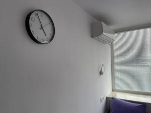 a clock hanging on a wall next to a window at BHN ТОП ЦЕНТЪР СТУДИО in Gabrovo