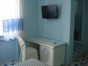 Habitación con escritorio y TV en la pared. en Hotel La Lampara, en Golfo Aranci