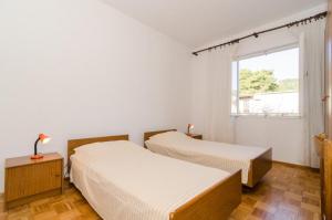 2 camas en una habitación blanca con ventana en Apartments Kuzma, en Smokvica