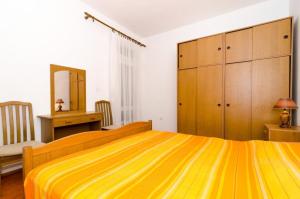 Un dormitorio con una gran cama amarilla y un escritorio en Apartments Kuzma, en Smokvica