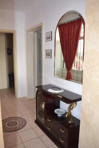 a bathroom with a vanity with a mirror and a red curtain at Villa Camelia in Torre Lapillo