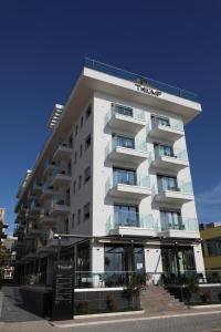 a white building with a sign in front of it at Hotel Bar Restaurant Triumf Shengjin in Shëngjin