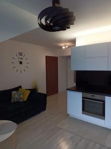 a living room with a couch and a clock on the wall at Apartament Kruklanki in Kruklanki