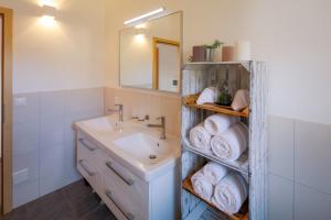 a bathroom with a sink and a mirror and towels at Modern and cosy 5 rooms penthouse with stunning view in Triesenberg