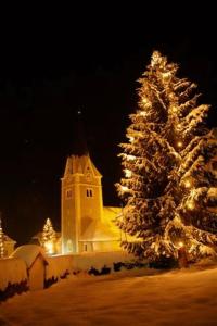 ein Weihnachtsbaum vor einer Kirche in der Nacht in der Unterkunft Gästehaus Freitag das kleine Hotel in Sankt Georgen