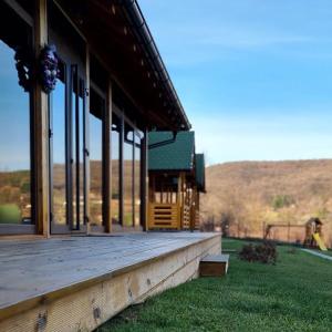 a large building with a wooden porch with windows at Imperator Kvintil apartmani & SPA in Ležimir