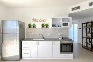 a kitchen with white cabinets and a stainless steel refrigerator at Europa Residence in Tiberias